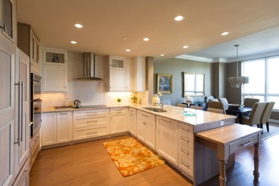 Inspiration for a large transitional u-shaped brown floor and medium tone wood floor open concept kitchen remodel in Denver with an undermount sink, shaker cabinets, white cabinets, granite countertops, white backsplash, mosaic tile backsplash, stainless steel appliances and a peninsula