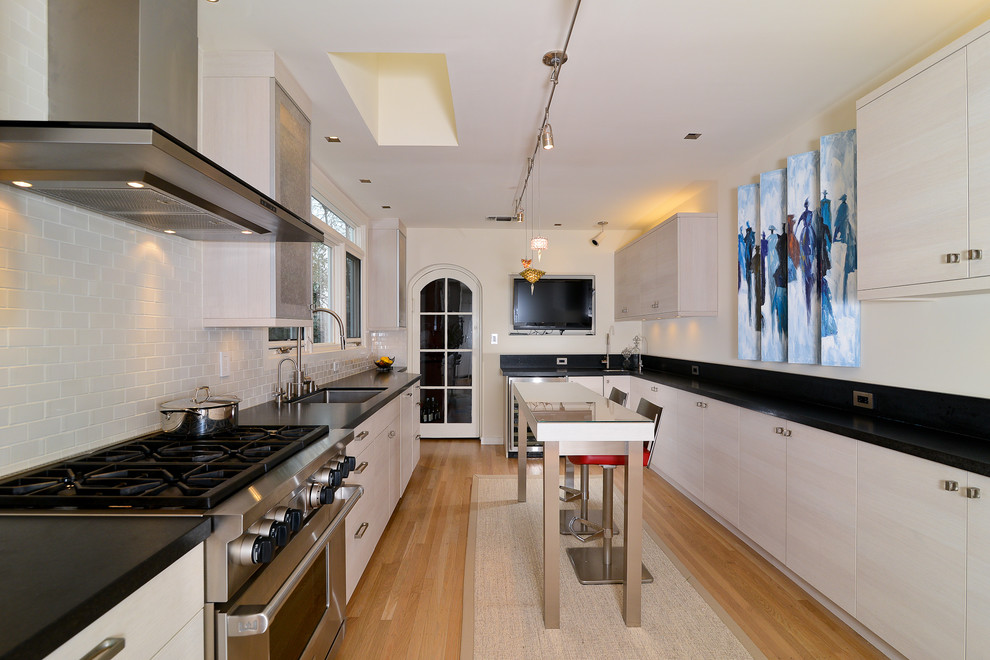 This is an example of a modern separate kitchen in Sacramento with an undermount sink, flat-panel cabinets, white cabinets, white splashback, subway tile splashback and stainless steel appliances.