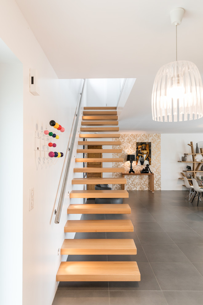 This is an example of a large contemporary wood straight staircase in Strasbourg with open risers and metal railing.