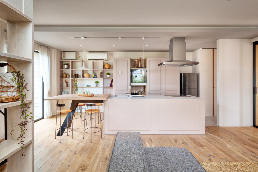 Scandi grey and cream single-wall open plan kitchen in Tokyo with a submerged sink, beaded cabinets, beige cabinets, laminate countertops, beige splashback, light hardwood flooring, an island, beige floors and grey worktops.