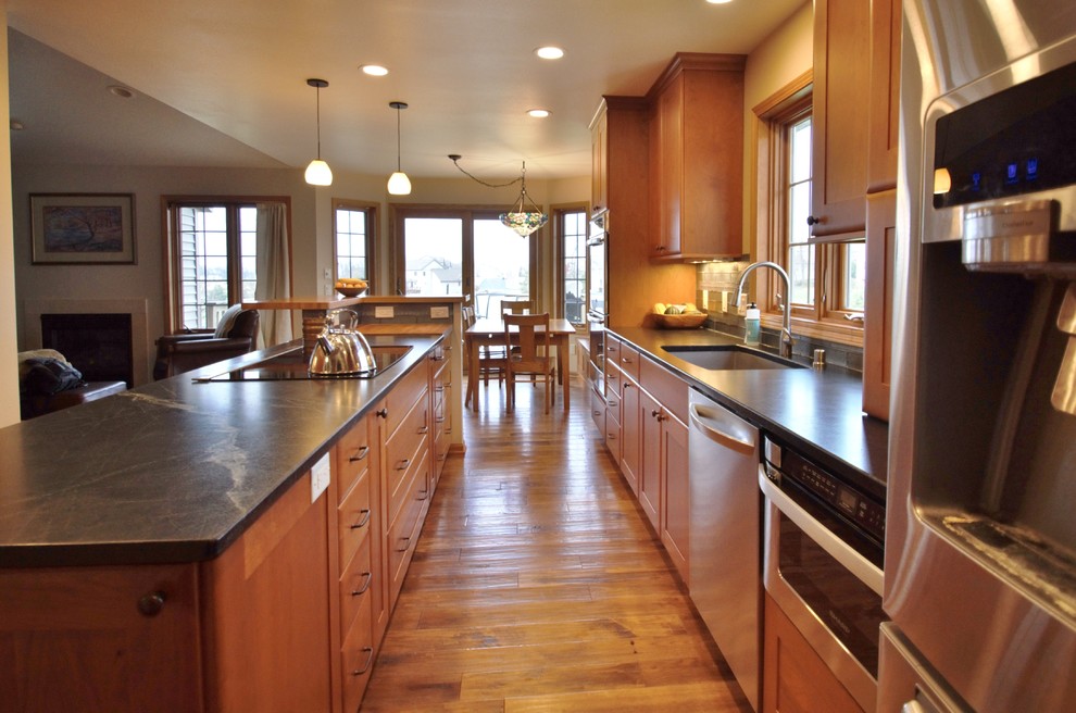 Eat-in kitchen - transitional galley medium tone wood floor eat-in kitchen idea with a double-bowl sink, recessed-panel cabinets, medium tone wood cabinets, soapstone countertops, stainless steel appliances and an island