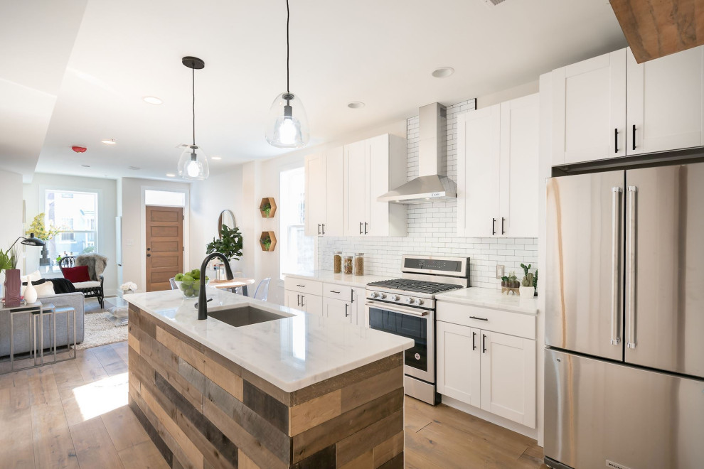 Inspiration for a contemporary galley eat-in kitchen in DC Metro with an undermount sink, shaker cabinets, white cabinets, quartz benchtops, white splashback, subway tile splashback, stainless steel appliances, medium hardwood floors, with island, brown floor and white benchtop.