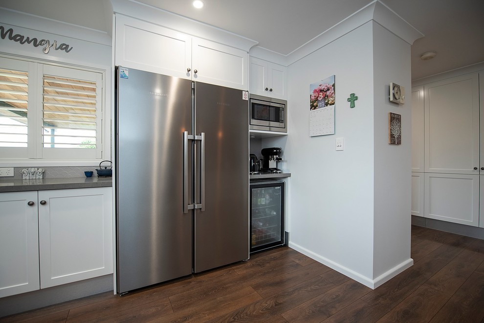 Large transitional u-shaped eat-in kitchen in Sydney with an undermount sink, shaker cabinets, white cabinets, quartz benchtops, grey splashback, porcelain splashback, stainless steel appliances, medium hardwood floors, a peninsula and grey benchtop.