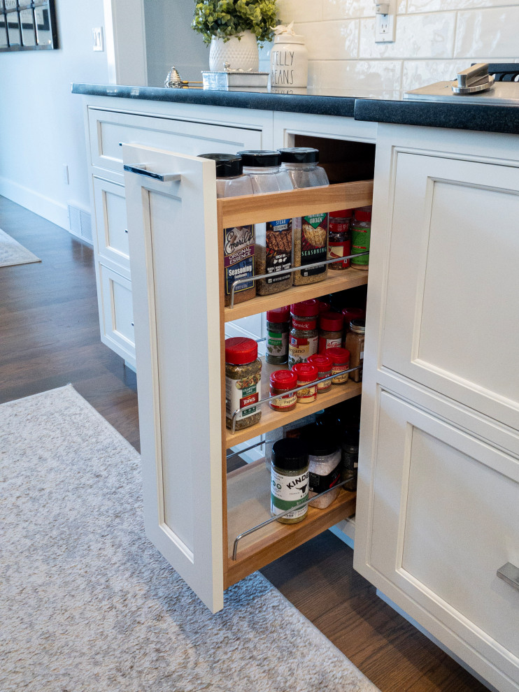 Inspiration for a large transitional l-shaped medium tone wood floor, gray floor and shiplap ceiling eat-in kitchen remodel with an undermount sink, flat-panel cabinets, white cabinets, granite countertops, yellow backsplash, subway tile backsplash, stainless steel appliances, an island and white countertops