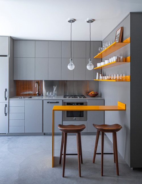 Compact handleless kitchen with matte grey flat-front cabinets, bright orange shelves, and a slim breakfast bar