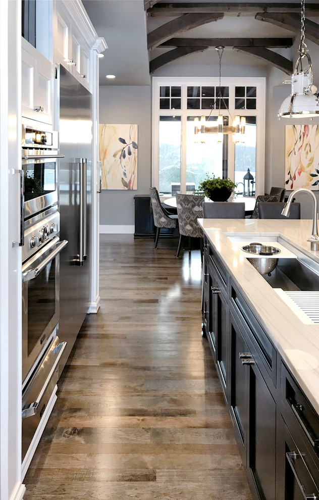 Large transitional u-shaped eat-in kitchen photo with marble backsplash and an island