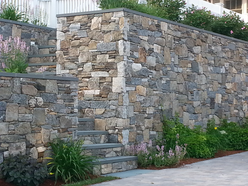 Photo of a mid-sized traditional front yard partial sun garden in Boston with a retaining wall and mulch.