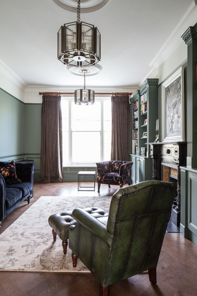 Mid-sized traditional enclosed living room in London with green walls, dark hardwood floors, a standard fireplace, a metal fireplace surround and brown floor.