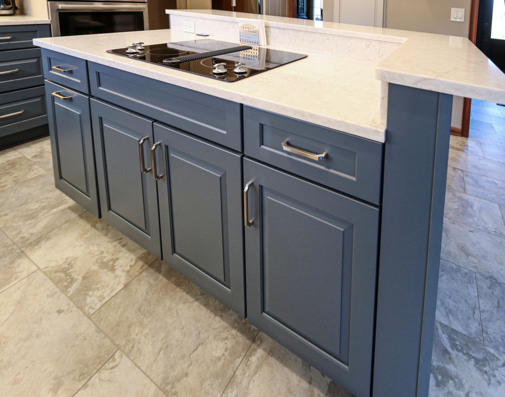 Photo of a mid-sized transitional galley eat-in kitchen in Cleveland with an undermount sink, raised-panel cabinets, blue cabinets, quartz benchtops, multi-coloured splashback, travertine splashback, stainless steel appliances, porcelain floors, with island, beige floor and beige benchtop.