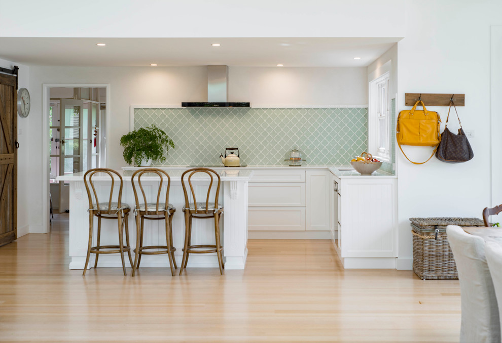 Design ideas for a mid-sized contemporary l-shaped open plan kitchen in Canberra - Queanbeyan with a drop-in sink, shaker cabinets, white cabinets, green splashback, light hardwood floors, with island, marble benchtops and porcelain splashback.