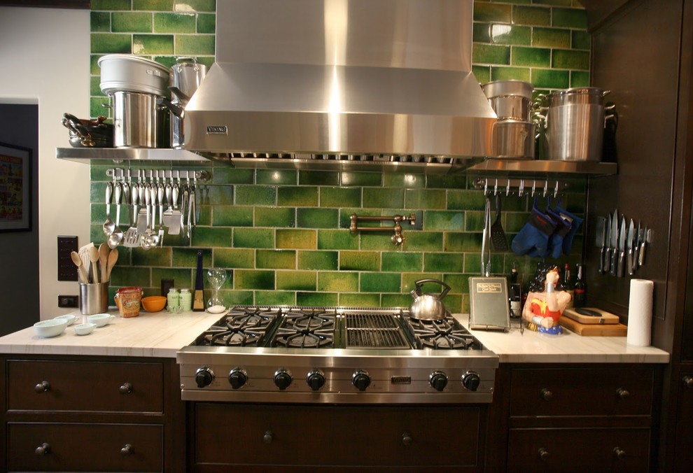 This is an example of a transitional separate kitchen in Los Angeles with dark wood cabinets, green splashback, subway tile splashback, stainless steel appliances and no island.