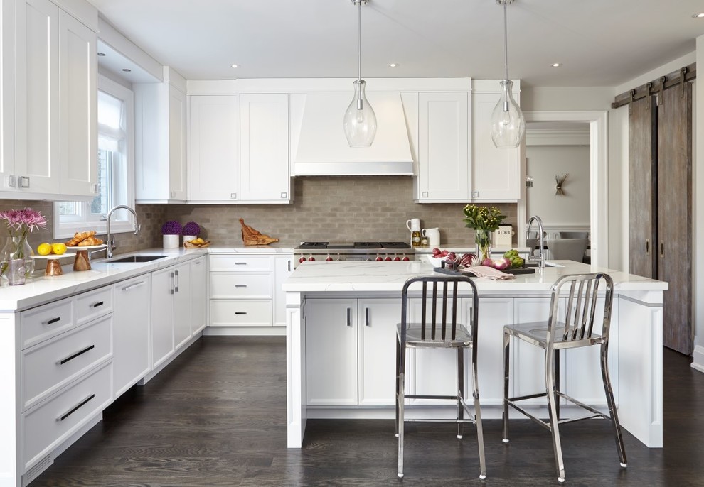 Inspiration for a transitional l-shaped dark wood floor and brown floor enclosed kitchen remodel in Toronto with a single-bowl sink, shaker cabinets, white cabinets, brown backsplash, stainless steel appliances, an island and white countertops