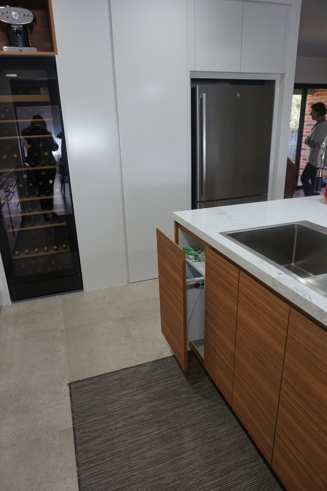 Mid-sized contemporary l-shaped eat-in kitchen in Sydney with a drop-in sink, white cabinets, quartz benchtops, white splashback, porcelain splashback, stainless steel appliances, ceramic floors and with island.