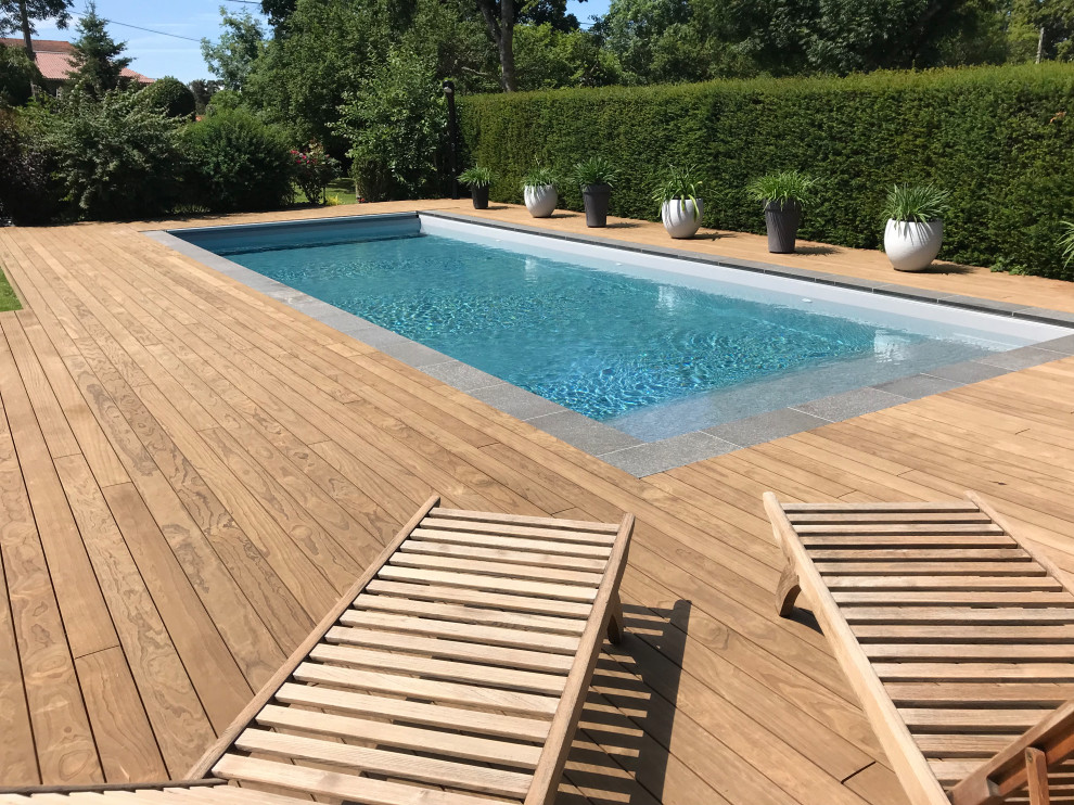 Ejemplo de piscina clásica renovada rectangular en patio trasero con paisajismo de piscina y entablado