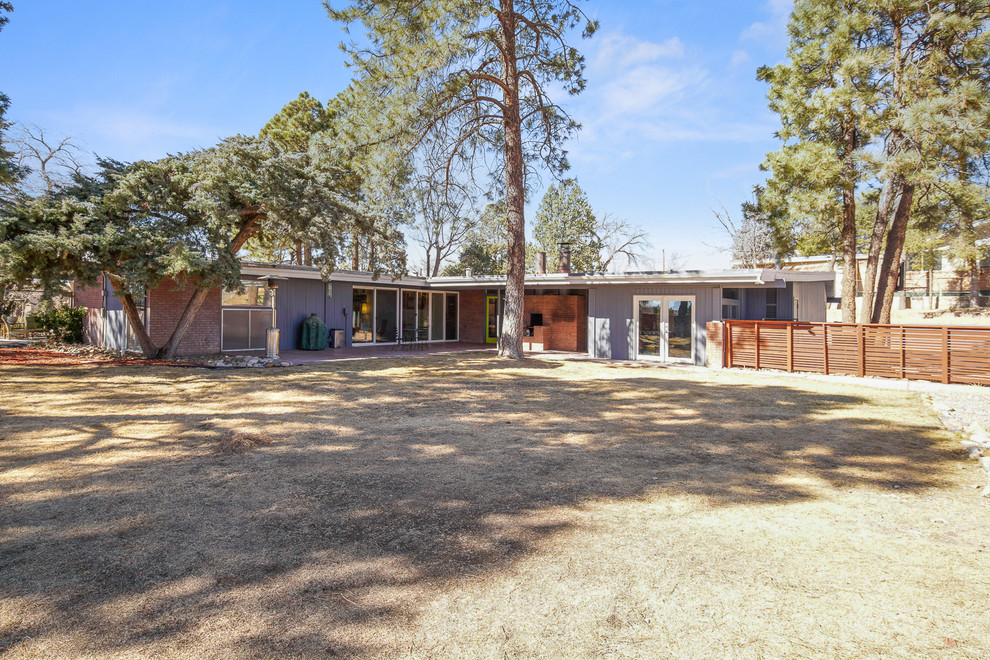 Expansive midcentury one-storey grey house exterior in Albuquerque with mixed siding, a flat roof and a mixed roof.