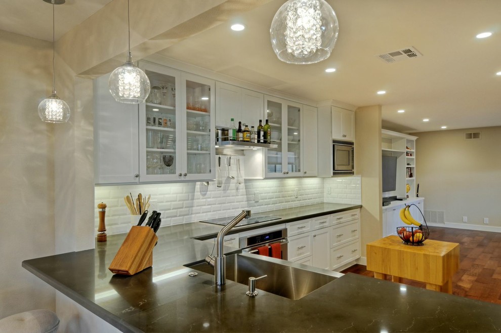 Mid-sized transitional galley medium tone wood floor open concept kitchen photo with a farmhouse sink, shaker cabinets, white cabinets, quartz countertops, white backsplash, ceramic backsplash, stainless steel appliances and no island