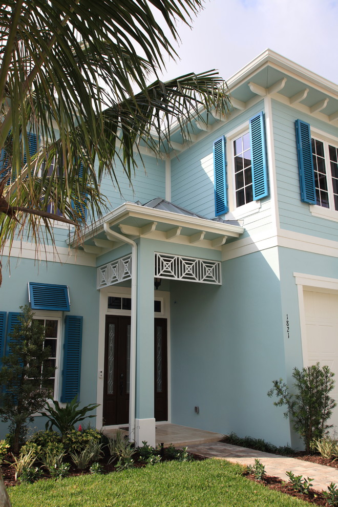 Large beach style two-storey stucco blue house exterior in Miami.
