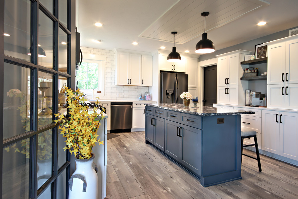 Photo of a mid-sized country u-shaped eat-in kitchen in Grand Rapids with an undermount sink, recessed-panel cabinets, white cabinets, quartz benchtops, white splashback, subway tile splashback, black appliances, vinyl floors, with island, grey floor and white benchtop.