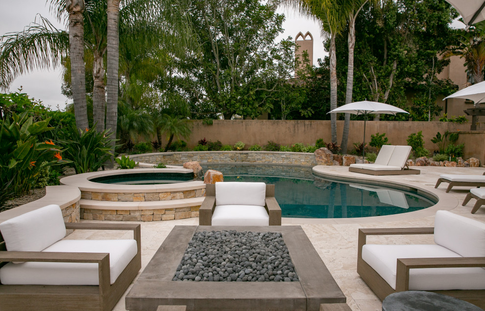 Design ideas for a mid-sized transitional backyard custom-shaped pool in San Diego with natural stone pavers.