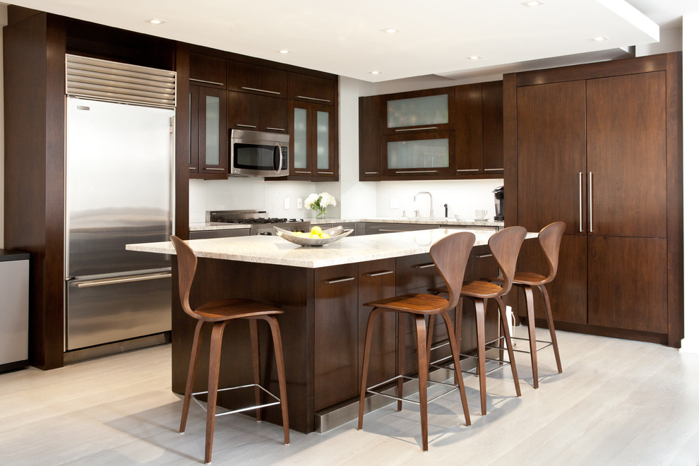 Photo of a contemporary l-shaped kitchen in New York with flat-panel cabinets, dark wood cabinets, white splashback, stainless steel appliances and with island.