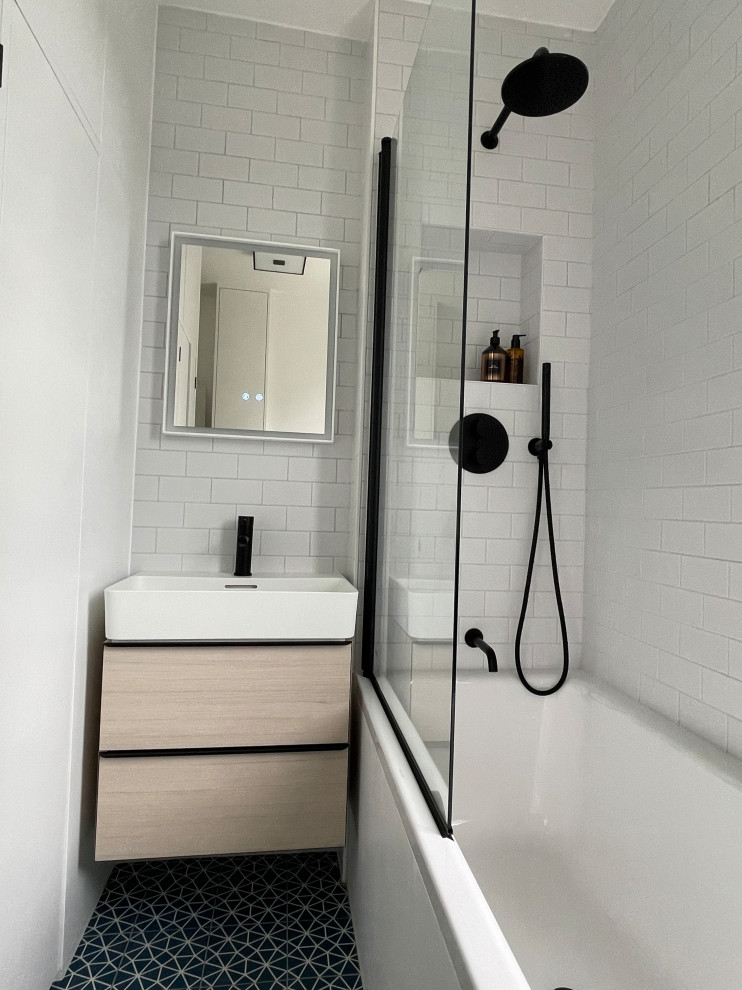 Стильный дизайн: маленькая детская ванная комната со стиральной машиной в современном стиле с плоскими фасадами, светлыми деревянными фасадами, накладной ванной, душем над ванной, раздельным унитазом, белой плиткой, керамогранитной плиткой, белыми стенами, полом из керамогранита, подвесной раковиной, синим полом, душем с распашными дверями, тумбой под одну раковину и подвесной тумбой для на участке и в саду - последний тренд