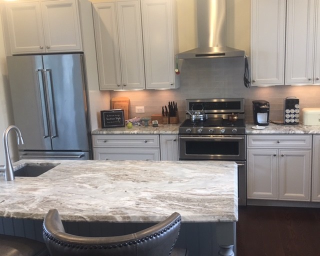 Inspiration for a mid-sized transitional l-shaped dark wood floor and brown floor eat-in kitchen remodel with a farmhouse sink, recessed-panel cabinets, gray cabinets, granite countertops, beige backsplash, subway tile backsplash, stainless steel appliances and an island