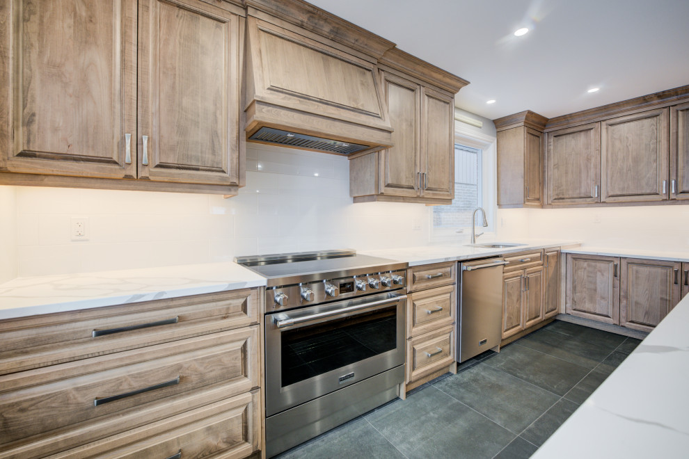Example of a mid-sized transitional l-shaped eat-in kitchen design in Toronto with an undermount sink, raised-panel cabinets, medium tone wood cabinets, quartz countertops, white backsplash, ceramic backsplash, stainless steel appliances, an island and white countertops