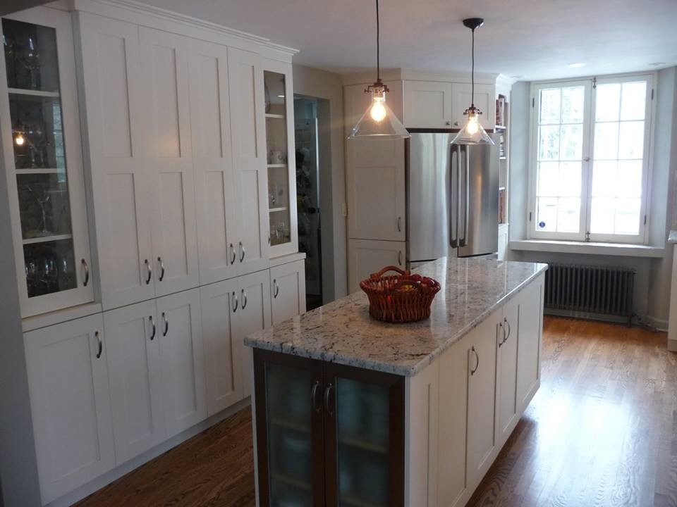 Inspiration for a large transitional u-shaped light wood floor home design remodel in Milwaukee with a farmhouse sink, recessed-panel cabinets, white cabinets, granite countertops, gray backsplash, subway tile backsplash, stainless steel appliances and an island