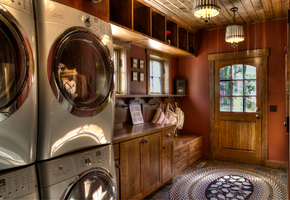 Design ideas for a mid-sized country utility room in Minneapolis with red walls and a stacked washer and dryer.