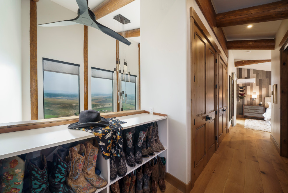 Mid-sized country gender-neutral built-in wardrobe in Denver with medium hardwood floors and exposed beam.