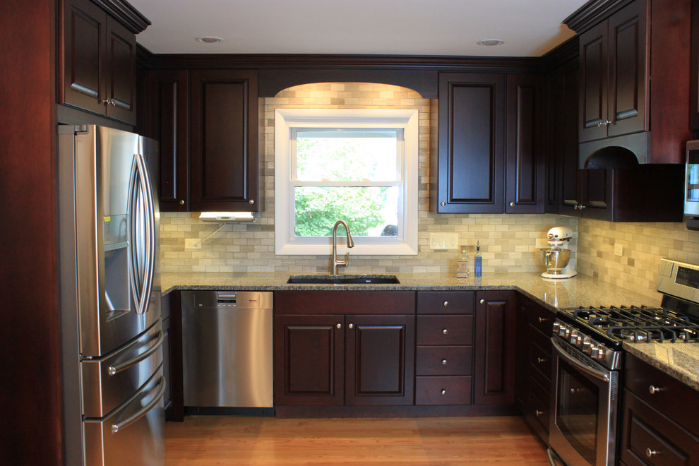 Mid-sized transitional u-shaped laminate floor eat-in kitchen photo with an undermount sink, raised-panel cabinets, dark wood cabinets, quartz countertops, gray backsplash, porcelain backsplash, stainless steel appliances and no island