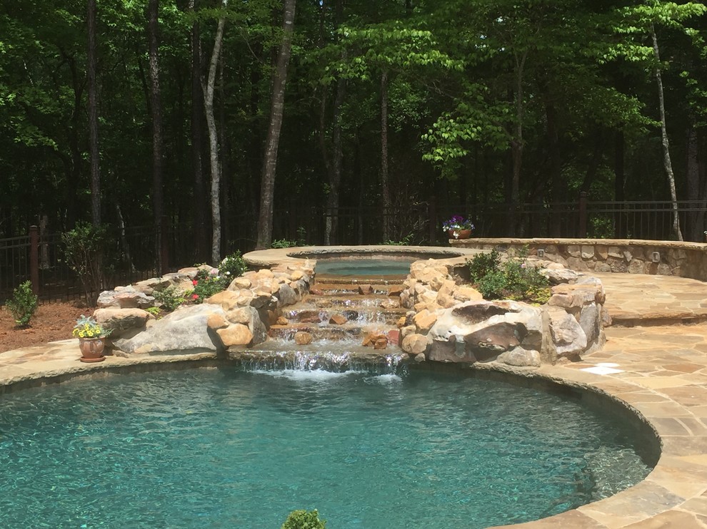 Example of a mid-sized mountain style backyard stone and custom-shaped natural hot tub design in Atlanta