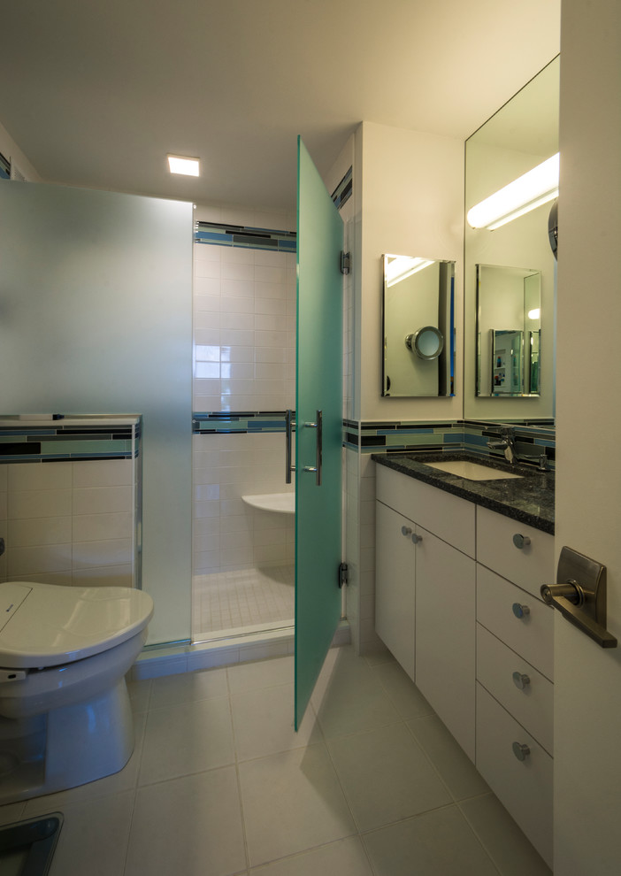 This is an example of a small contemporary master bathroom in Baltimore with flat-panel cabinets, an alcove shower, a two-piece toilet, white tile, white walls, ceramic floors, an undermount sink, engineered quartz benchtops and a hinged shower door.