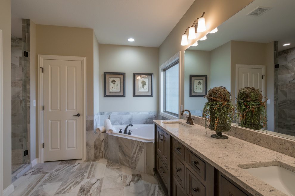 Mid-sized country master bathroom in Other with shaker cabinets, dark wood cabinets, a corner tub, a shower/bathtub combo, a two-piece toilet, beige tile, ceramic tile, beige walls, ceramic floors, an undermount sink, granite benchtops, grey floor and a hinged shower door.