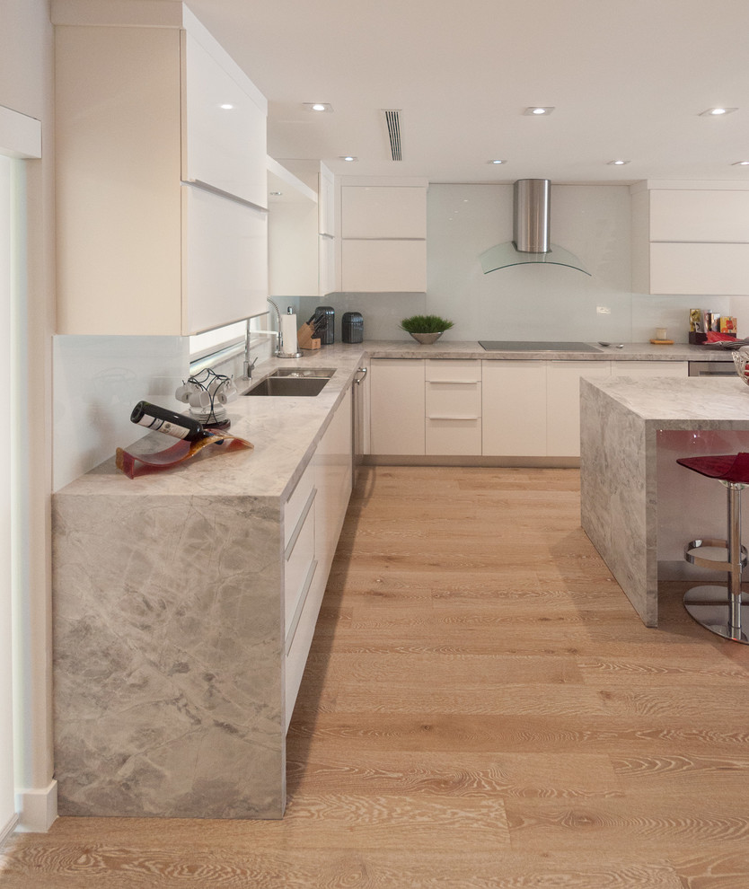Photo of a mid-sized contemporary eat-in kitchen in Miami with a drop-in sink, flat-panel cabinets, white cabinets, marble benchtops, white splashback, glass tile splashback, stainless steel appliances and porcelain floors.