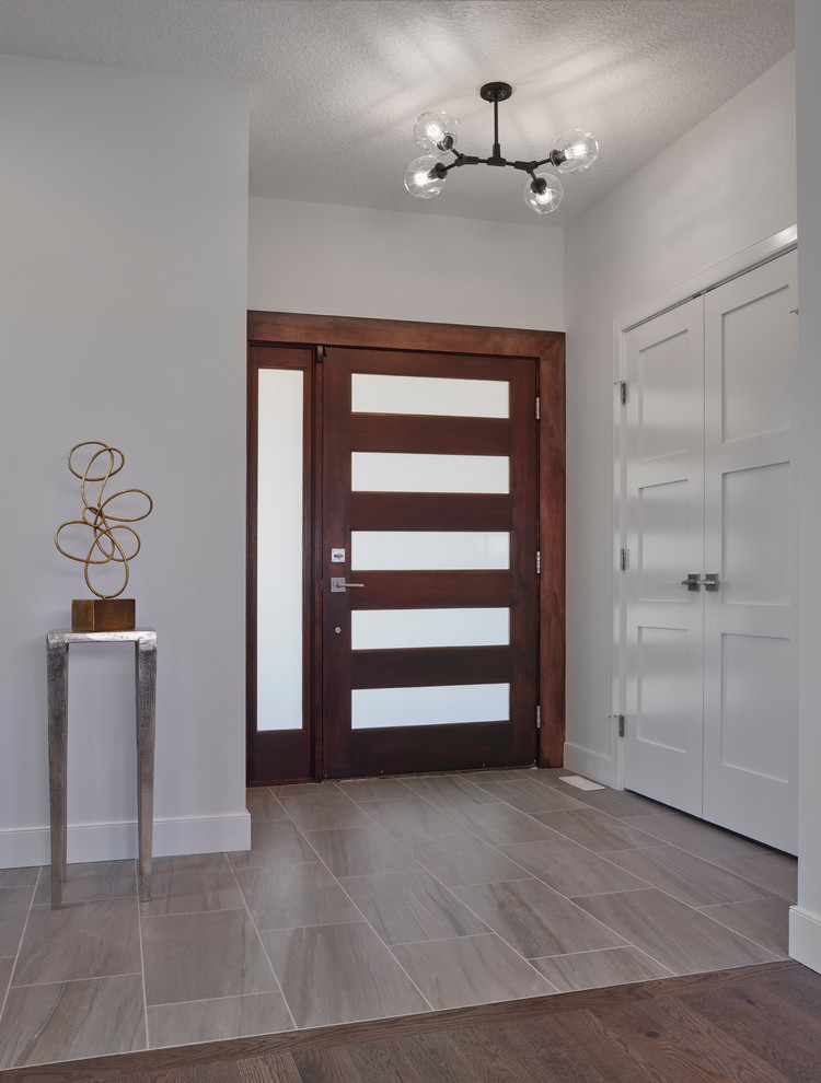 Photo of a mid-sized transitional foyer in Edmonton with grey walls, ceramic floors, a pivot front door, a dark wood front door and grey floor.
