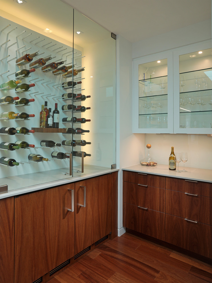 This is an example of a small contemporary l-shaped home bar in Tampa with flat-panel cabinets, medium wood cabinets, quartz benchtops, glass sheet splashback and dark hardwood floors.