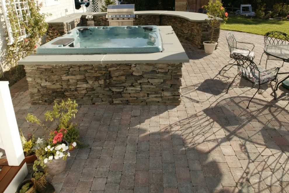 Photo of a mid-sized traditional backyard patio in New York with an outdoor kitchen and natural stone pavers.