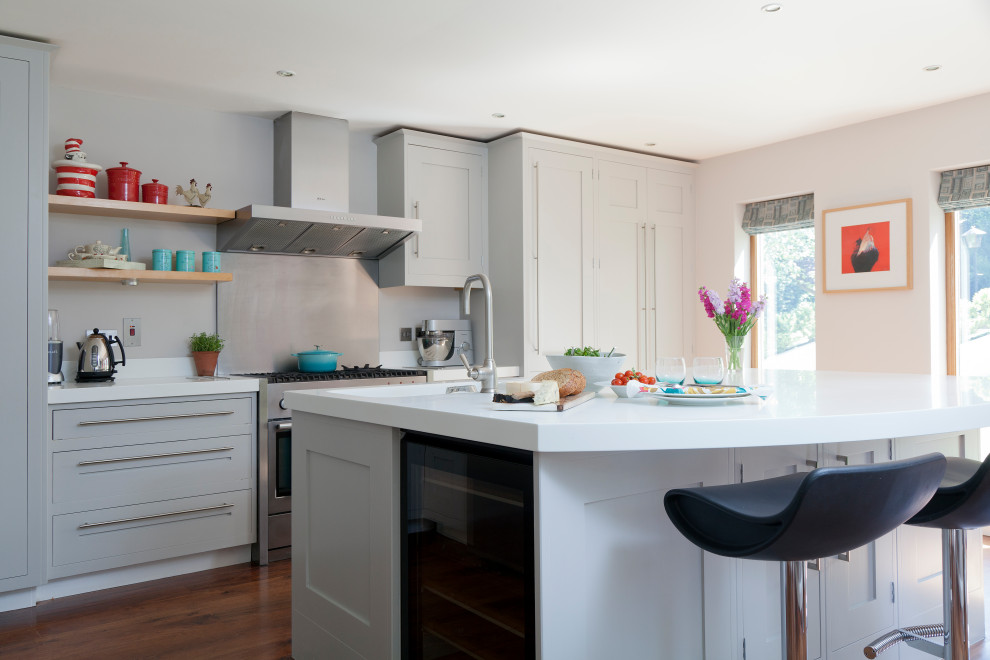 Inspiration for a mid-sized transitional galley kitchen in Kent with an integrated sink, shaker cabinets, grey cabinets, metallic splashback, metal splashback, stainless steel appliances, medium hardwood floors, with island, brown floor and white benchtop.