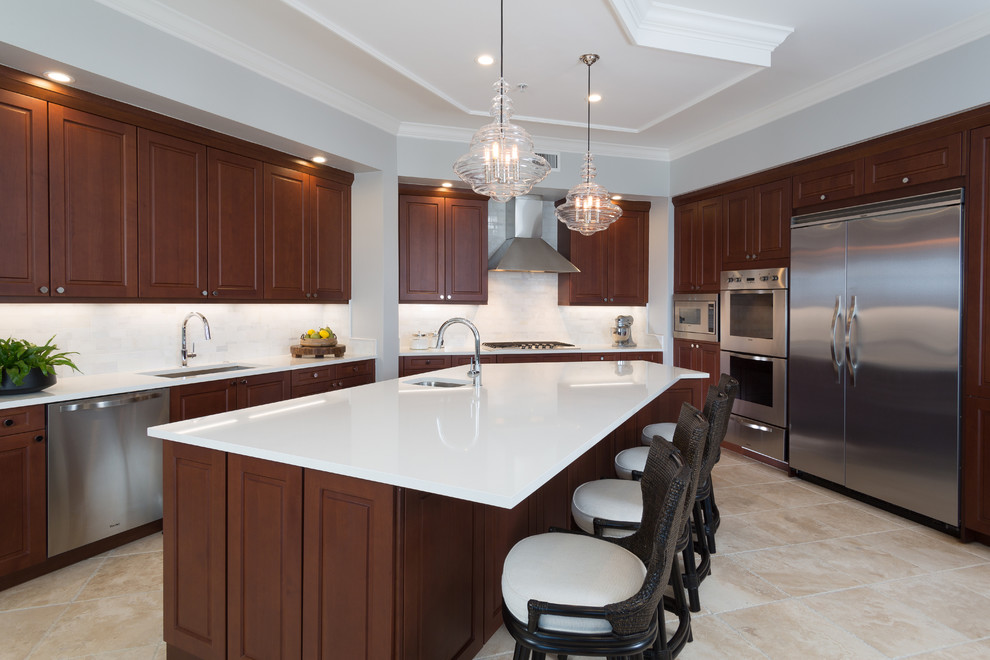 Large transitional u-shaped separate kitchen in Orlando with an undermount sink, raised-panel cabinets, dark wood cabinets, solid surface benchtops, white splashback, marble splashback, stainless steel appliances, travertine floors, with island, beige floor and white benchtop.