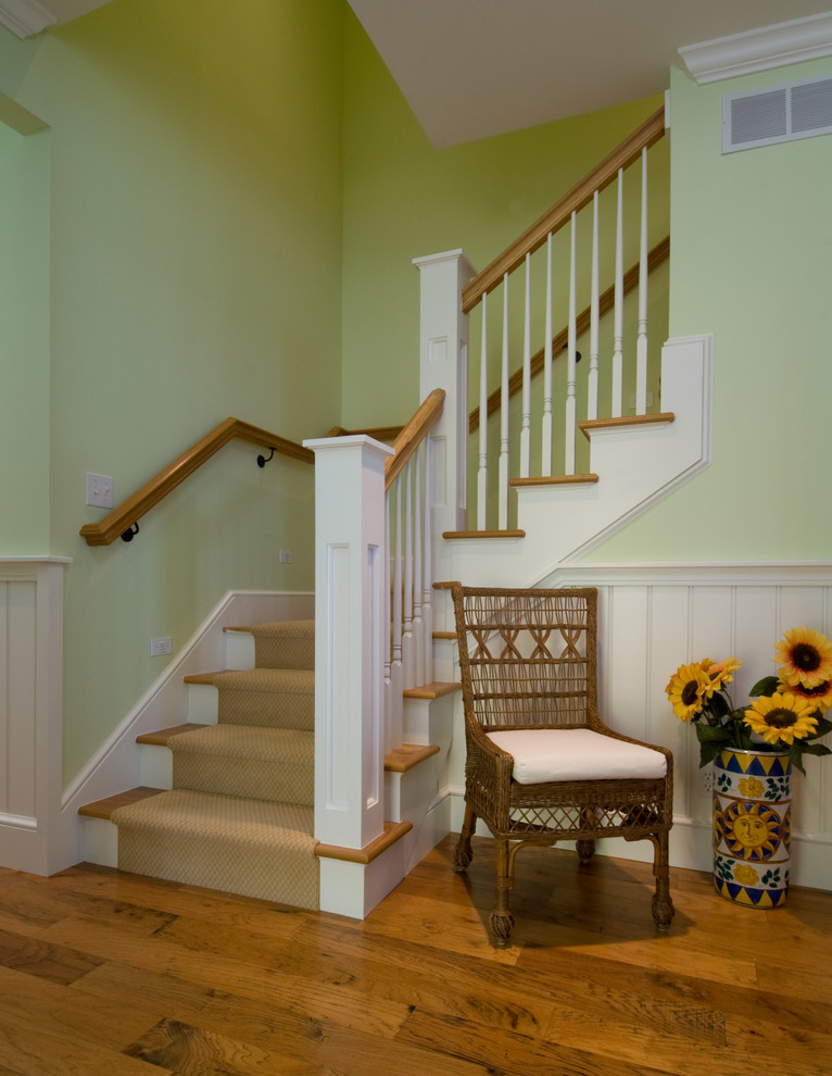 Photo of a mid-sized beach style wood l-shaped staircase in Other with carpet risers, wood railing and decorative wall panelling.