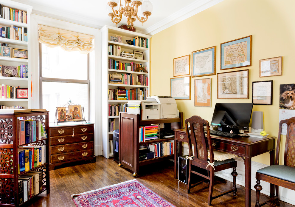 Photo of a mid-sized traditional home office in New York with yellow walls, dark hardwood floors, a freestanding desk and brown floor.