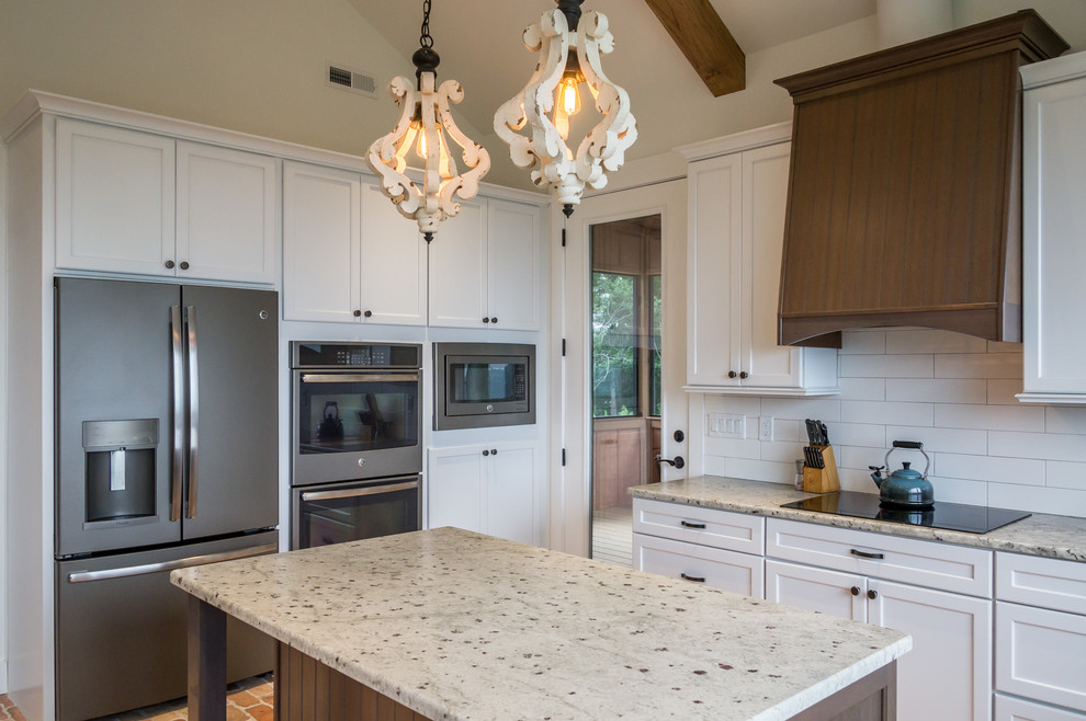 Open concept kitchen - large rustic u-shaped brick floor and brown floor open concept kitchen idea with a farmhouse sink, shaker cabinets, white cabinets, granite countertops, white backsplash, ceramic backsplash, stainless steel appliances, an island and beige countertops