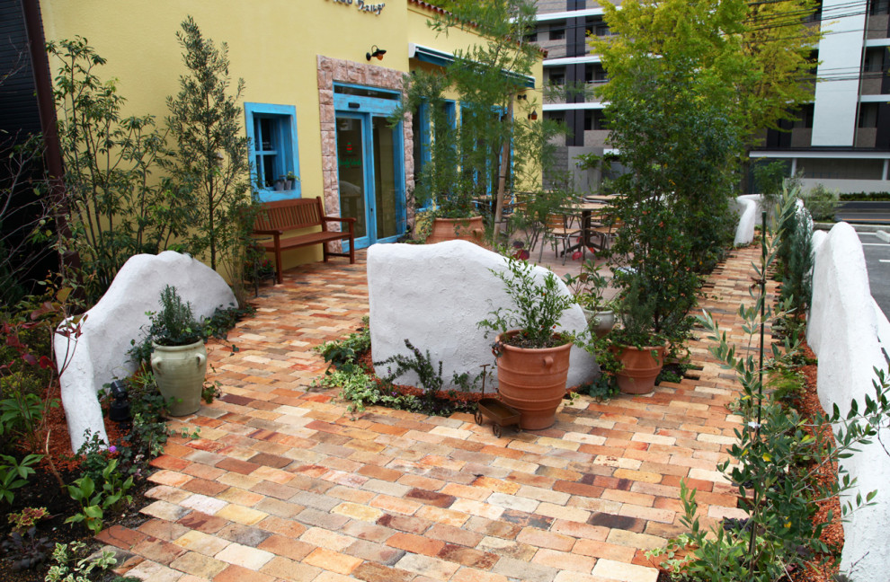 Ispirazione per un patio o portico mediterraneo di medie dimensioni e davanti casa con pavimentazioni in mattoni e un parasole