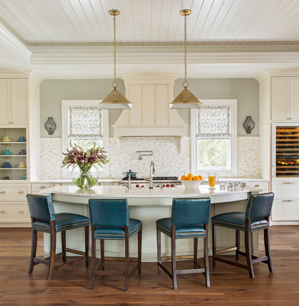 Photo of a large traditional single-wall open plan kitchen in Charleston with a farmhouse sink, shaker cabinets, beige cabinets, white splashback, stainless steel appliances, medium hardwood floors and with island.