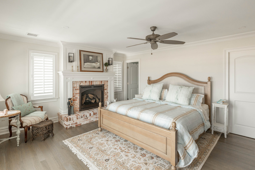 Cette image montre une chambre parentale traditionnelle avec un mur blanc, un sol en bois brun, une cheminée standard, un manteau de cheminée en brique et un sol marron.