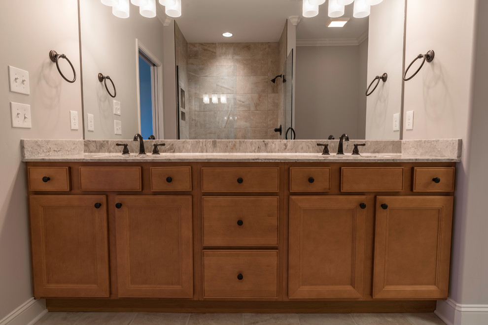 Inspiration for a mid-sized transitional master beige tile and ceramic tile ceramic tile alcove shower remodel with shaker cabinets, medium tone wood cabinets, granite countertops, beige walls and an undermount sink