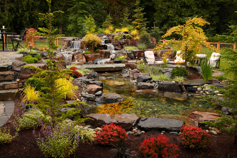 Photo of a country backyard garden in Seattle with with waterfall and natural stone pavers.