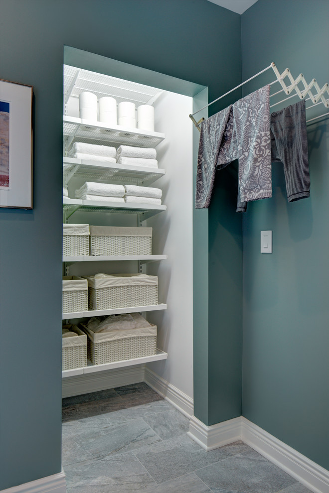 This is an example of a small transitional single-wall dedicated laundry room in New York with shaker cabinets, white cabinets, green walls, porcelain floors and grey floor.