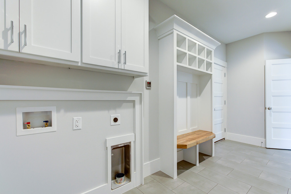 Inspiration for a large country galley utility room in Raleigh with an utility sink, shaker cabinets, white cabinets, grey walls, porcelain floors, a side-by-side washer and dryer and grey floor.